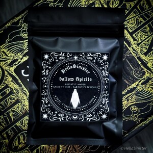 Handmade charcoal incense cones scattered beside black packaging labeled “Hollow Spirits” by HellaSinister, featuring oud, patchouli, and amber incense cones displayed on a dark gothic background.