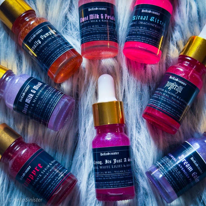 Brightly labeled vegan shimmer body oil samples on faux fur – HellaSinister mini perfume oils for layering or gifting
