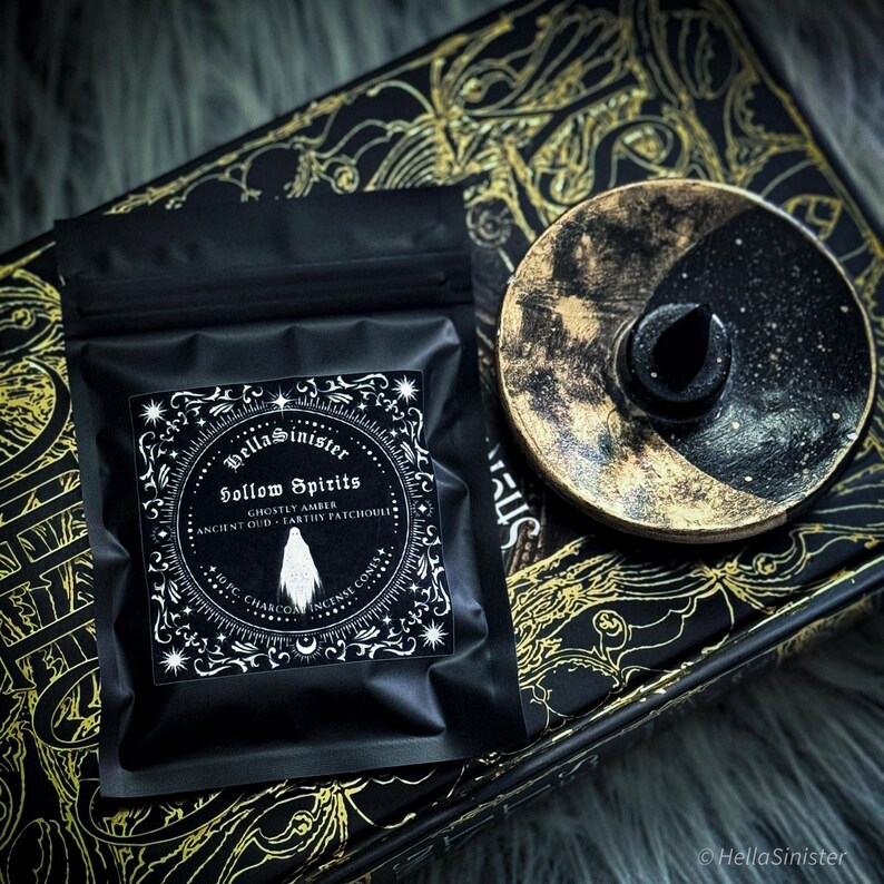 Handmade charcoal incense cones scattered beside black packaging labeled “Hollow Spirits” by HellaSinister, featuring oud, patchouli, and amber incense cones displayed on a dark gothic background.