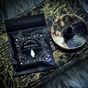 Handmade charcoal incense cones scattered beside black packaging labeled “Hollow Spirits” by HellaSinister, featuring oud, patchouli, and amber incense cones displayed on a dark gothic background.