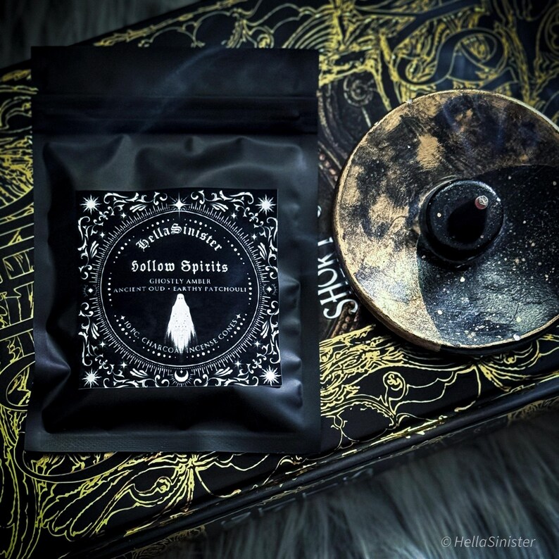 Handmade charcoal incense cones scattered beside black packaging labeled “Hollow Spirits” by HellaSinister, featuring oud, patchouli, and amber incense cones displayed on a dark gothic background.