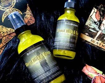 Può includere: Due bottiglie di olio per il corpo profumato "Ghost Milk & Nanas" con liquido giallo ed etichette nere. Le etichette presentano il testo "HellaSinister" e informazioni sul prodotto. Le bottiglie sono su una superficie scura e strutturata.