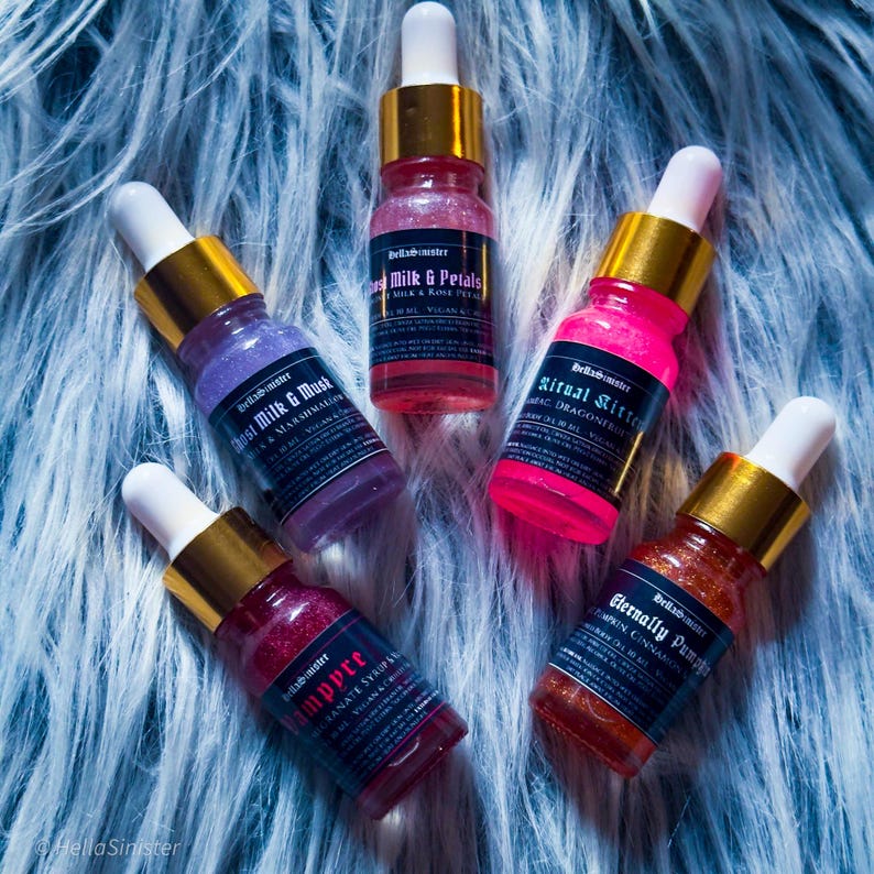 Five shimmery mini perfume body oil bottles in colorful tones on fur background – indie perfume oils for layering or gifting