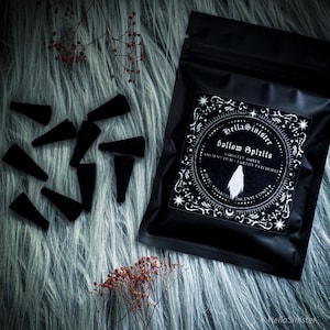 Handmade charcoal incense cones scattered beside black packaging labeled “Hollow Spirits” by HellaSinister, featuring oud, patchouli, and amber incense cones displayed on a dark gothic background.
