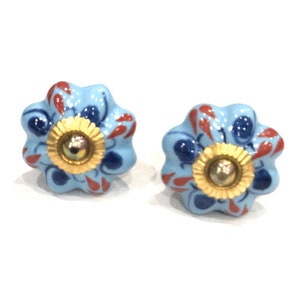 May include: Two blue ceramic drawer knobs with a floral design. The knobs have a gold center and red and blue accents.