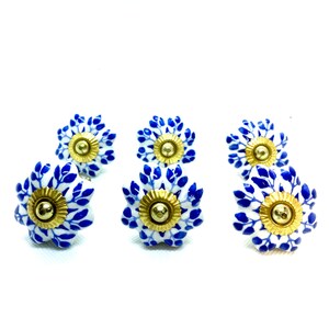 May include: Six blue and white ceramic drawer knobs with gold accents. Each knob features a floral design with a central gold button.