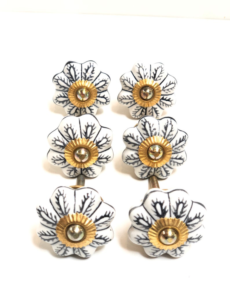 以下が含まれることがあります： 黒の花柄と金色のアクセントが付いた白いセラミック製の引き出しノブ6個セット。各ノブには取り付け用のネジが付いています。