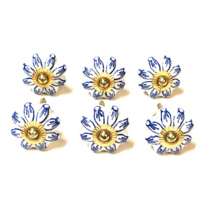 Peut inclure: Six boutons de tiroir en céramique blanche avec un motif floral bleu et des accents dorés.