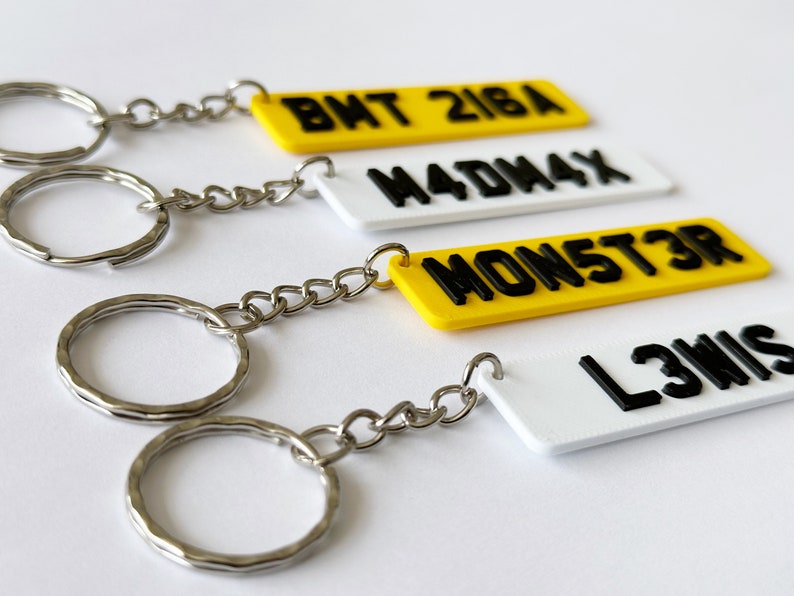 May include: Four keychains with black lettering on yellow and white rectangular tags. The tags have the following text: BHT 218A, M4DW4X, MON5T3R, L3WIS.
