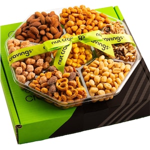May include: A clear plastic tray filled with an assortment of nuts, including almonds, peanuts, and walnuts. The tray is divided into sections and tied with a green ribbon that reads "nutcravings". The tray sits on a green and black box.