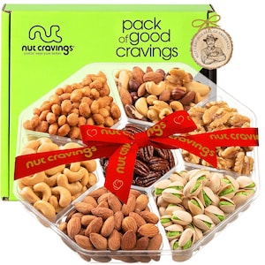 May include: A clear plastic tray with six compartments filled with different types of nuts. The tray is tied with a red ribbon with the words "nut cravings" printed on it. The tray is surrounded by a green box with the words "pack of good cravings" printed on it.