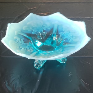 Könnte beinhalten: Eine antike blaue und weiße opaleszierende Glasschüssel mit gewelltem Rand und drei Füßen.