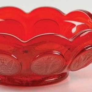May include: A vibrant red glass bowl with a handle. The bowl has a scalloped rim and is decorated with embossed circular designs. The handle is a loop shape, and the bowl sits on a small, round base. The glass has a glossy finish.