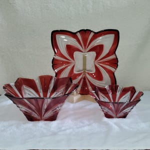 May include: Set of three glass bowls with a red and white swirl design. The bowls are square and have a scalloped edge.