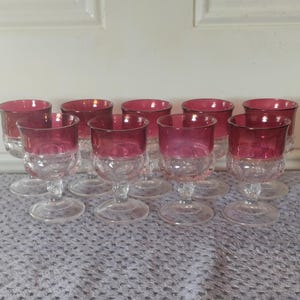 以下が含まれることがあります： ルビーレッドの縁取りが施された透明なガラスのステム付きゴブレット10個セット。ゴブレットはテクスチャ加工が施されています。