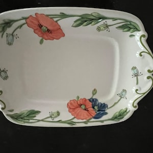 Puede incluir: Plato rectangular blanco para servir con un diseño floral. El plato presenta un borde de vides y hojas verdes, con flores coral y azules. Los bordes del plato tienen un diseño festoneado.