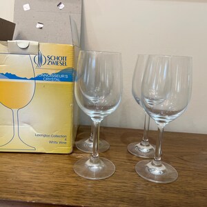 K&ouml;nnte beinhalten: Vier klare Weingl&auml;ser aus Glas auf einer Holzoberfl&auml;che. Die Gl&auml;ser sind alle gleich gro&szlig; und haben die gleiche Form, und sie sind alle leer. Die Gl&auml;ser sind in einer Reihe angeordnet, wobei das erste Glas in der Reihe etwas n&auml;her am Betrachter ist als die anderen drei. Die Gl&auml;ser sind alle aus klarem Glas und haben einen leicht abgerundeten Boden. Die Gl&auml;ser sind alle leer und sauber.