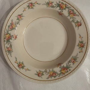 Puede incluir: Un tazón de sopa de cerámica blanca con un borde dorado y un patrón floral con rosas rosas, amarillas y verdes.