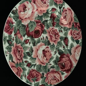 Può includere: Piatto ovale in ceramica con fondo bianco e un motivo floreale di rose rosa e bordeaux con foglie verdi.