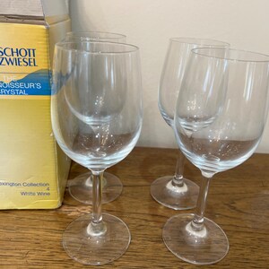 K&ouml;nnte beinhalten: Vier klare Wei&szlig;weingl&auml;ser aus Glas der Lexington Collection von Schott Zwiesel. Das Logo The Connoisseur's Crystal ist auf der Schachtel zu sehen.