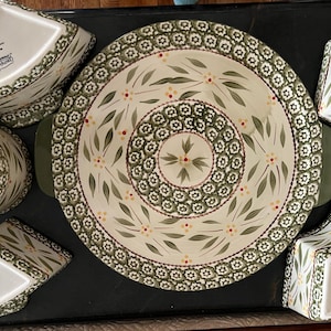 May include: A set of green and white ceramic serving dishes with a floral pattern. The set includes a large platter, four small bowls, and four small dishes.