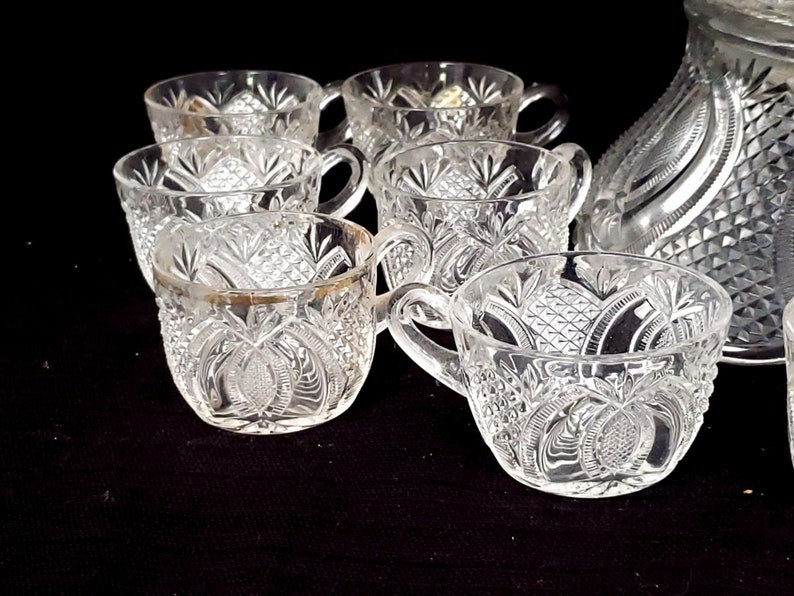 May include: A set of eight clear glass punch cups with a cut glass design. The cups have a gold rim and are ideal for serving punch or other beverages.