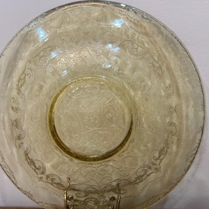 May include: A yellow glass bowl with a delicate floral pattern. The bowl has a scalloped edge and a center well.