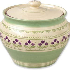 Puede incluir: Un cuenco de cerámica con tapa, en tonos crema y verde, adornado con motivos florales morados. El cuenco tiene asas y es adecuado para servir alimentos. Medidas en cm.