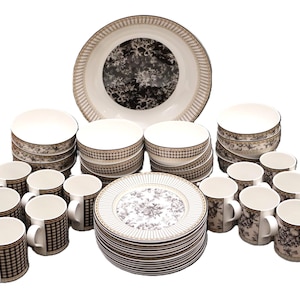May include: A dinnerware set featuring white ceramic plates, bowls, and mugs decorated with black and white floral patterns and checkered borders. The collection includes multiple stacks of plates and bowls alongside several matching handled mugs.