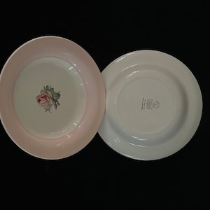 May include: Two white ceramic plates, one with a pink rim and a floral design, the other with a white rim and the text "Made in England" on the bottom.