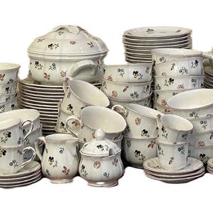 May include: A complete white porcelain dinnerware set with a floral pattern in black, red, and green. The set includes plates, bowls, cups, saucers, serving dishes, and a teapot, perfect for a formal dining experience.