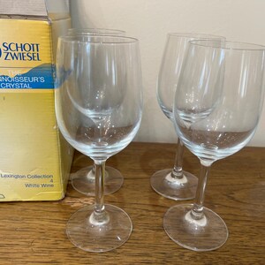 K&ouml;nnte beinhalten: Vier klare Wei&szlig;weingl&auml;ser aus der Schott Zwiesel Lexington Collection. Die Gl&auml;ser stehen auf einer Holzoberfl&auml;che.