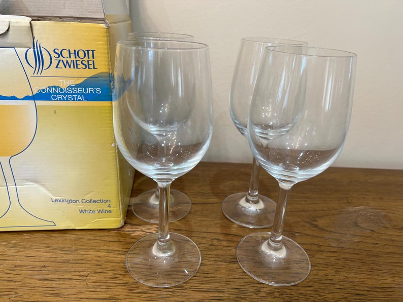 K&ouml;nnte beinhalten: Vier klare Wei&szlig;weingl&auml;ser aus der Schott Zwiesel Lexington Collection. Die Gl&auml;ser stehen auf einer Holzoberfl&auml;che.