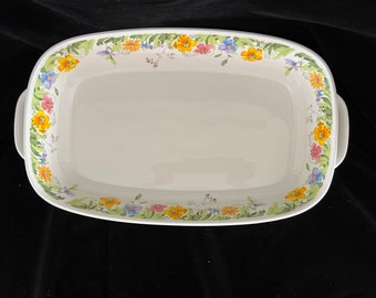 Puede incluir: Fuente rectangular de cerámica blanca con asas. El borde está decorado con un estampado floral con flores amarillas, rosas y azules y hojas verdes. Diseñada para hornear y servir.