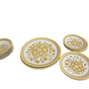 May include: A set of vintage dinnerware featuring a floral design in shades of yellow and white. The set includes several plates and bowls, perfect for serving meals. The plates have a diameter of approximately 10 inches.