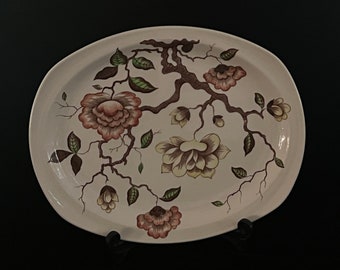 Puede incluir: Un plato ovalado de cerámica blanca con un diseño floral. El diseño presenta ramas marrones con flores rosas y amarillas y hojas verdes.