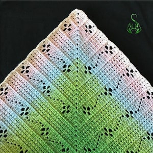 Puede incluir: Una manta de bebé de ganchillo con un degradado de rosa, azul, verde y blanco. La manta tiene un delicado patrón floral.