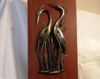 Vintage wall decor, pair of bronzed herons & bullrushes mounted on woodgrain board, brass corners, made in West Germany circa 1960s or 1970s