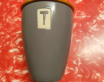 MCM style ceramic two-tone tea caddy, grey glazed with stencilled "T" and blonde wood lid with retro metal knob, circa 2000s.