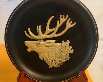 Mid-century Cold War era West German wall plaque, gloss-painted reindeer & oak leaves in relief on black hard plastic disc, circa 1960s.