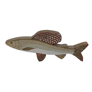 May include: A wooden toy fish with a brown and white spotted body and a red and brown spotted fin. The fish is painted with a realistic design.