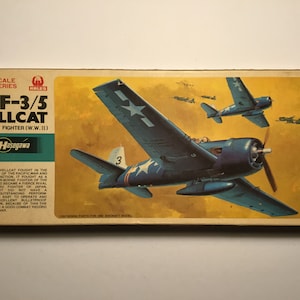 Op de afbeelding: Een modelbouwdoos voor een 1/72 schaal Hasegawa F6F-3/5 Hellcat U.S. Navy jachtvliegtuig. De doos heeft een kleurrijke illustratie van het vliegtuig in de lucht met de tekst "F6F-3/5 Hellcat U.S. Navy Fighter (W.W. II)" en "Hasegawa" gedrukt op de voorkant.