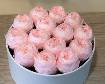 May include: A white round box filled with pink roses. The roses are arranged in a circle around the edge of the box.