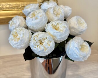 May include: A bouquet of white silk roses in a silver vase. The roses are arranged in a cluster and have a realistic appearance.