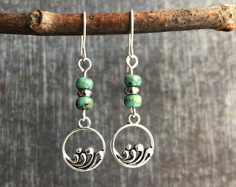 May include: Silver dangle earrings with turquoise beads and a wave design.