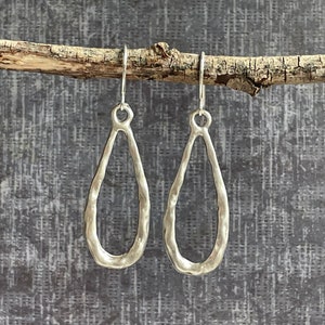 May include: A pair of silver teardrop-shaped earrings with a hammered texture.