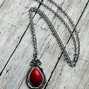 Peut inclure: Un collier en cha&icirc;ne argent avec un pendentif en pierre rouge et turquoise. Le pendentif est en forme de larme et poss&egrave;de un cadre argent&eacute; d&eacute;coratif.