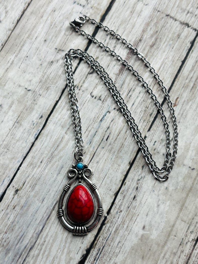 Peut inclure: Un collier en cha&icirc;ne argent avec un pendentif en pierre rouge et turquoise. Le pendentif est en forme de larme et poss&egrave;de un cadre argent&eacute; d&eacute;coratif.