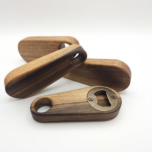 K&ouml;nnte beinhalten: Drei Flaschen&ouml;ffner aus Holz mit einem Flaschen&ouml;ffner-Einsatz aus Messing. Die Flaschen&ouml;ffner sind aus dunklem Holz mit einem gestreiften Muster.