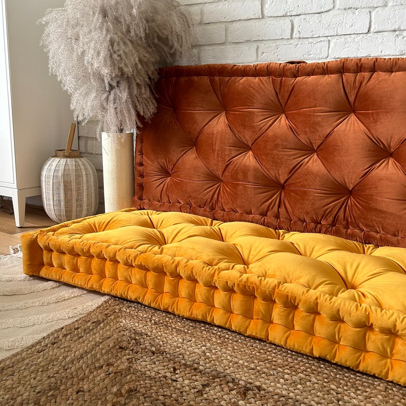 Peut inclure: Un grand coussin de sol jaune capitonn&eacute; avec un dossier capitonn&eacute; brun. Le coussin est en velours et a une forme carr&eacute;e.